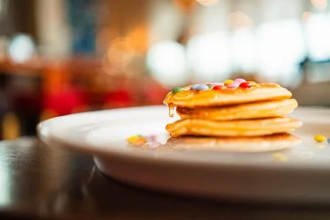 Drop of Honey Dripping Down a Stack of Pancakes with Colorful Topping Choco.. Stock Photos