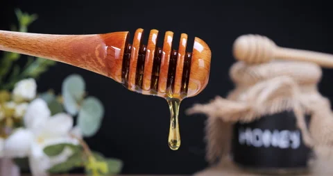Drop of honey dripping from the spoon on black background Stock Footage 233994592