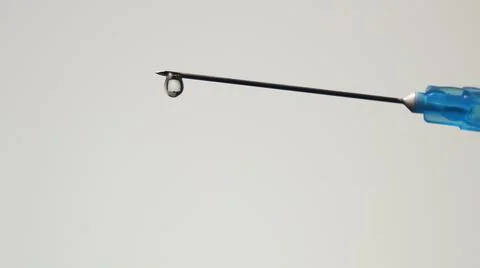 Drop of injection solution at the end of a sharp needle of a syringe Stock Photos