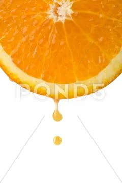 Drop of juice falling from orange half isolated Stock Photos