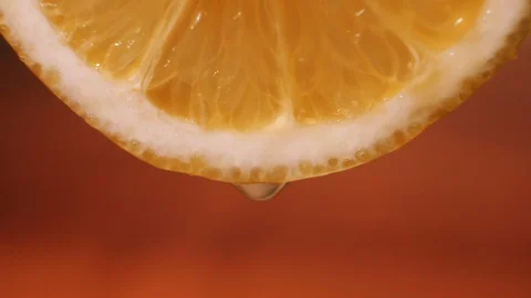 A drop of juice flows down from a slice of orange, macro, close up. Bright juicy Stock Footage 127853222