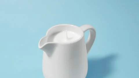 A drop of milk drips into a full milk jug Stock Footage 152167863