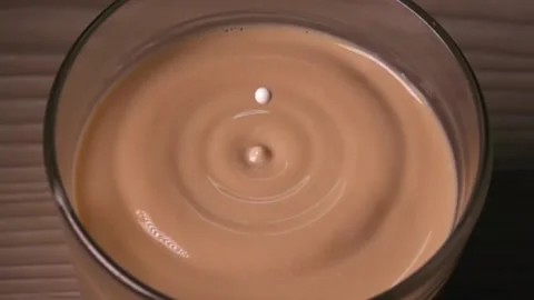 A drop of milk falls into a cup of coffee in super slow motion Stock Footage 230896689