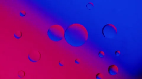 A drop of oil connects with another drop on a blue and red gradient background Stockbeeldmateriaal 303058751