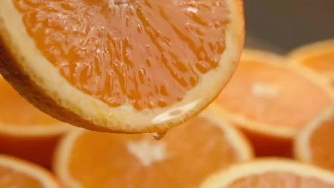 A drop of orange juice drips from the cut of an orange half Stock Footage 296581853