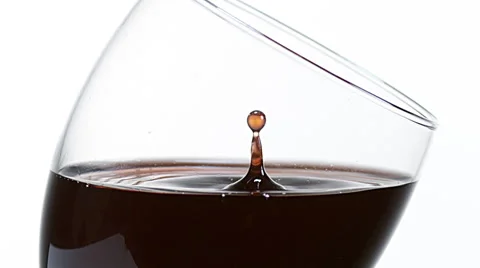 Drop of Red Wine being poured into Glass, against White Background, Slow motion Stock Footage