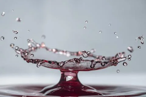 Drop of red wine collision creates explosive crown sculpture on a water surface Stock Photos