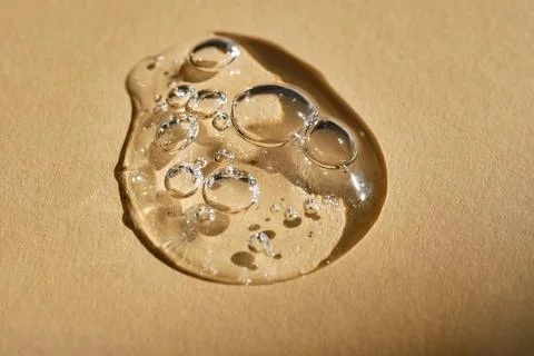 A drop of serum on a beige background. Stock Photos