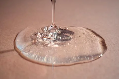 A drop of serum with bubbles on a beige background. Stock Photos