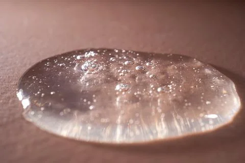A drop of serum with bubbles on a beige background. Stock Photos