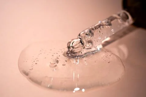 A drop of serum with bubbles on a beige background. Stock Photos