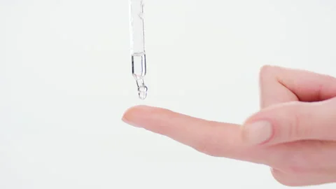 Drop of skincare serum falls down from dropper on forefinger Stock Footage 155630247