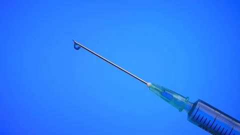 Drop on syringe needle on a blue background. Medicine concept. Stock Footage 129706168