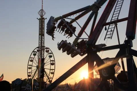 Drop tower, ferries wheel, and pendulum ride at sunset Stock Photos