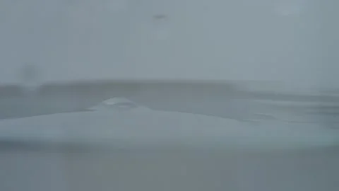 Drop of water causes ripples and bubbles in a glass of clear water Stock Footage 327583254