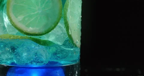 Drop of water drips down the cocktail glass in slow motion on the dark Video stock 158384023