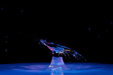 Drop of water falling down in the water Фото