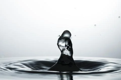 Drop of water falling down in the water Stock Photos