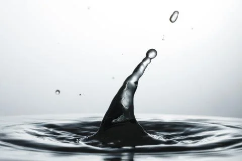Drop of water falling down in the water Stock Photos