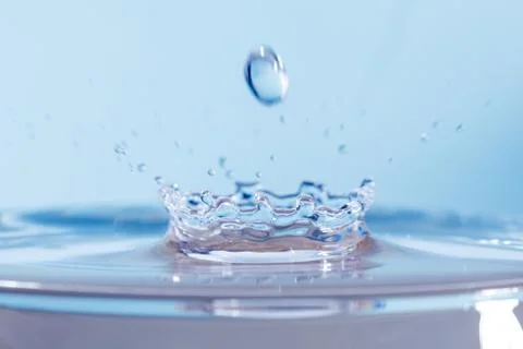 Drop of water falling down in the water Stock Photos