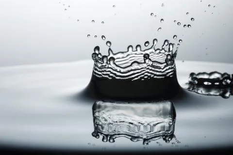 Drop of water falling down in the water Stock Photos