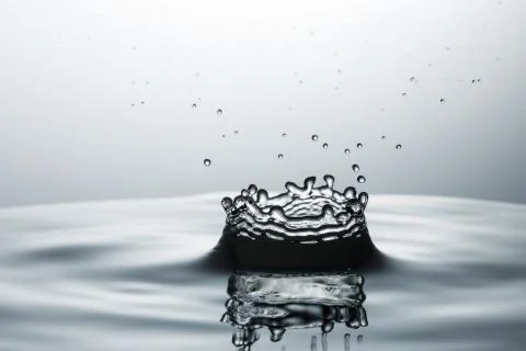 Drop of water falling down in the water Fotos de archivo