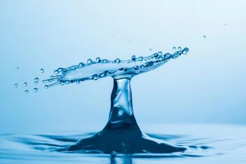 Drop of water falling down in the water Stock Photos