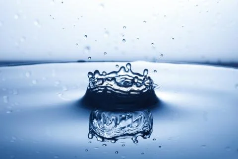 Drop of water falling down in the water Stock Photos