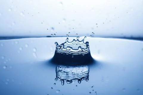 Drop of water falling down in the water Stock Photos