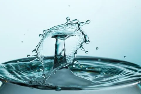 Drop of water falling down in the water Stock Photos
