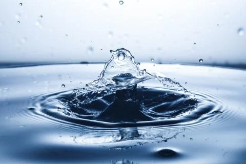 Drop of water falling down in the water Stock Photos