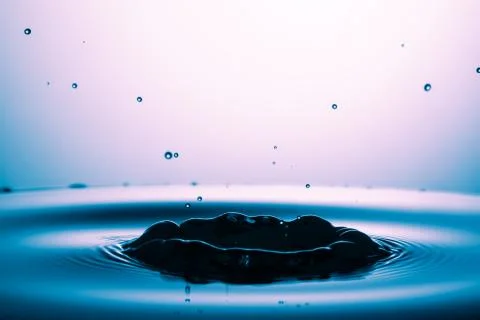 Drop of water falling down in the water 库存照片