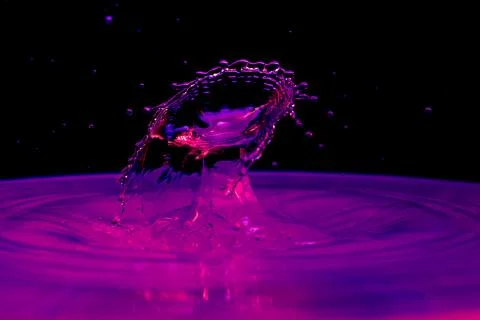 Drop of water falling down in the water Stock Photos