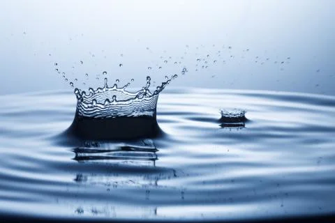 Drop of water falling down in the water Stock Photos