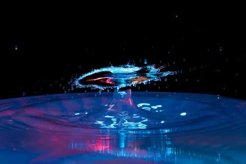 Drop of water falling down in the water Stock Photos