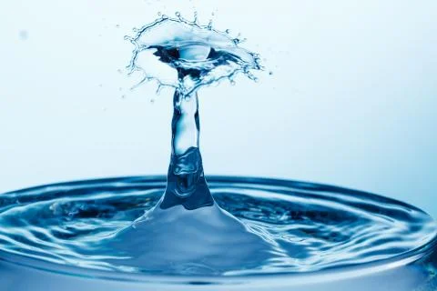 Drop of water falling down in the water Stock Photos