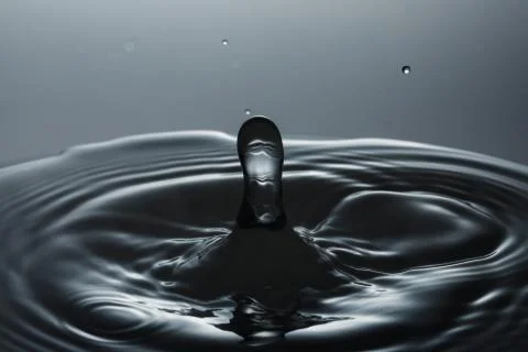 Drop of water falling down in the water Fotos Stock