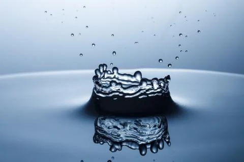 Drop of water falling down in the water Stock Photos