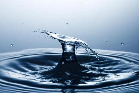 Drop of water falling down in the water Stock Photos