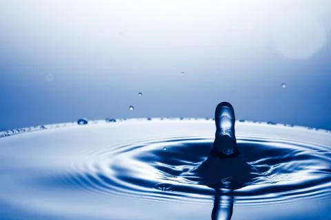Drop of water falling down in the water 库存照片