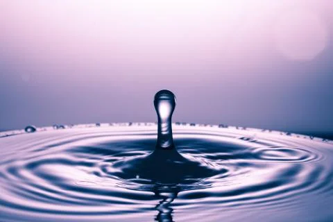 Drop of water falling down in the water Stock Photos