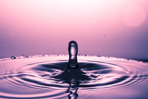 Drop of water falling down in the water Stock Photos
