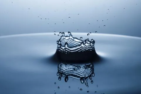 Drop of water falling down in the water Stock Photos