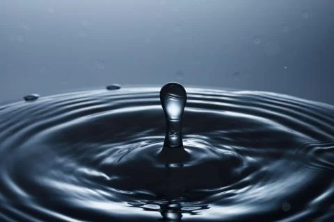 Drop of water falling down in the water Stock Photos