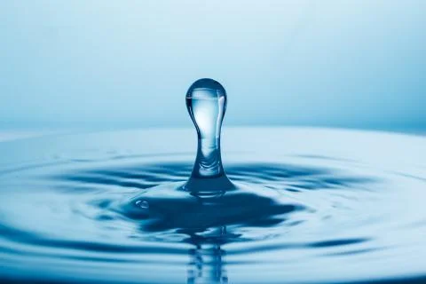 Drop of water falling down in the water Stock Photos