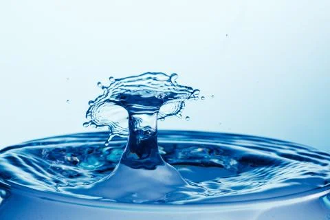 Drop of water falling down in the water Stock Photos