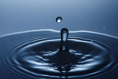 Drop of water falling down in the water 写真素材