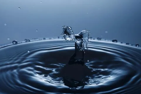 Drop of water falling down in the water Stock Photos
