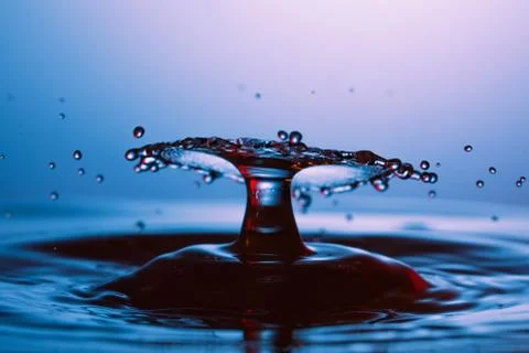 Drop of water falling down in the water Stock Photos