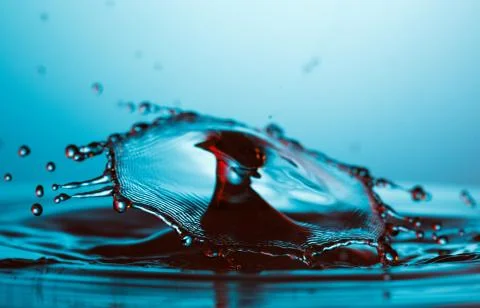 Drop of water falling down in the water Stock Photos